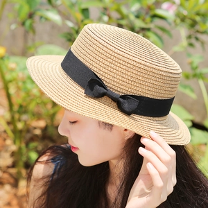 Cappello di paglia a cima piatta per bambini con fiocco nero, indossato in un giardino soleggiato