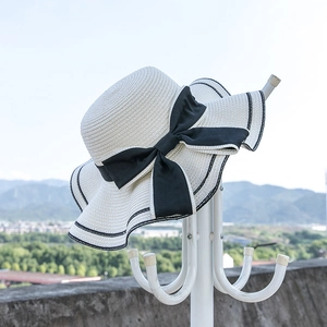 Women's summer straw sun hat with large black bow and striped brim for beach sun protection