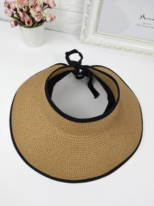 Top-down view of woven straw sun visor with black piping and rear ribbon bow detail