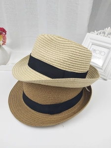 Chapeaux de paille beiges et marrons avec ruban noir sur fond à rayures blanches