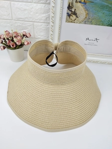 Detail of light beige straw sun visor hat showing woven texture and black elastic band