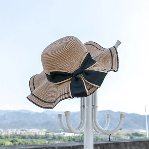 Detailed close-up of woven straw hat texture with black ribbon bow and wavy brim edge