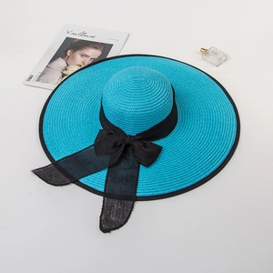 Close-up of turquoise wide-brim straw hat with black mesh bow tie and refined weaving