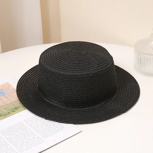 Close-up of black straw boater hat texture on a white table for summer sun protection