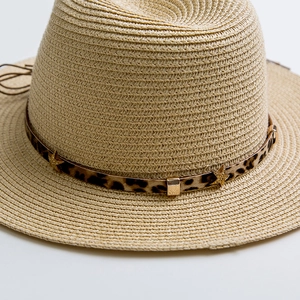 Detail of straw hat featuring leopard print band with gold star and metal buckle