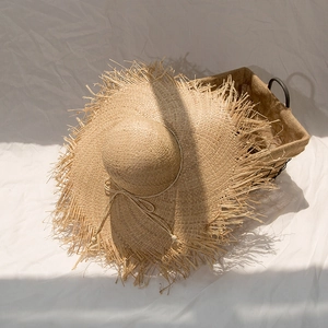 Detailed close-up of raffia sun hat with frayed brim and decorative wooden beads