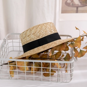 Close-up of flat-top straw hat with black ribbon in a cozy indoor setting