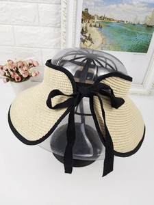 Detail of summer straw sun visor with black ribbon bow and contrasting edge trim