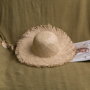 Détail du chapeau en paille de raphia aux bords effilochés avec accessoires d'été