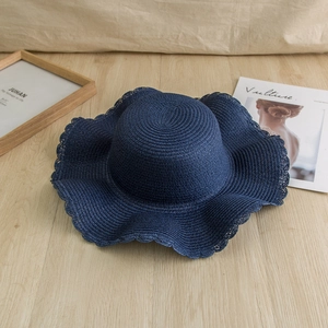 Navy blue wide brim straw hat with wavy edges for sun protection on summer beach holidays