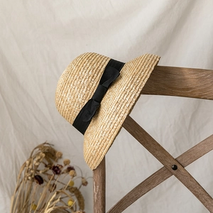 Ethnic dome straw sun hat with black ribbon on a wooden chair background