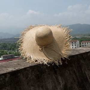 Ethnic wide brim raffia straw hat with raw edges and drawstring bow for outdoor sun protection