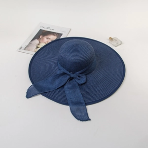 Detail of navy blue straw sun hat with large silk bow decoration and wide brim style