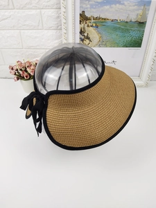 Detail of khaki straw sun visor hat featuring black ribbon bow and thick woven texture