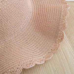 Close-up of wave-edged scalloped crochet trim on a woven straw sun hat for women
