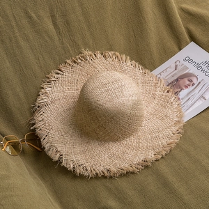 Détail d'un chapeau de paille en raphia à larges bords avec bordure à franges et accessoires