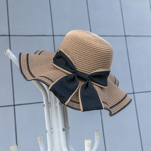 Detail of khaki straw sun hat with large black fabric bow and wavy striped brim