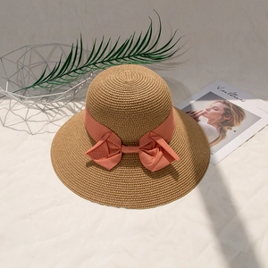 Close-up of woven straw hat texture with an elegant pink ribbon bow detail