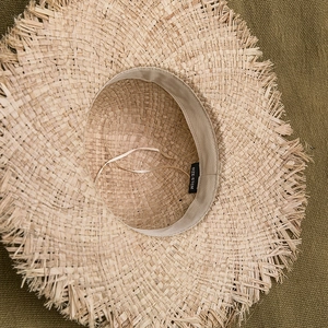 Détail intérieur d'un chapeau de soleil en raphia avec bandeau et étiquette de taille