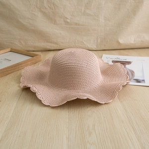 Close-up of pink paper straw sun hat with wavy scalloped edge detail for beach vacations