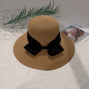 Detailed close-up of straw sun hat with woven texture and a large black bow ornament