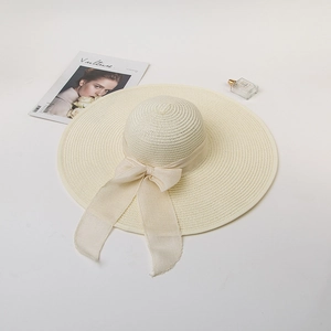 Elegant wide brim straw hat with beige ribbon bow and stylish magazine on white background