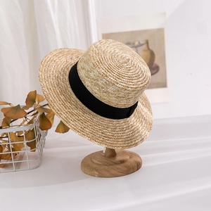 Classic straw boater hat with a flat top and wide black ribbon on a wooden hat stand