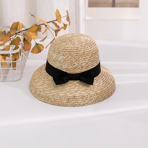 Close-up of handwoven straw sun hat with black bow detail and retro dome design