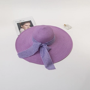 Detail of elegant purple wide-brim straw hat with ribbon bow and chic magazine prop