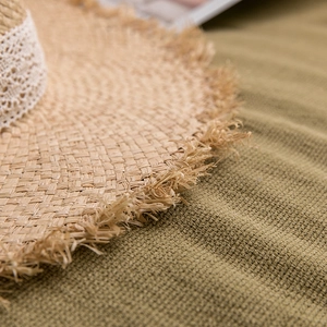 Detail of raffia straw hat with delicate white lace ribbon and frayed edge brim