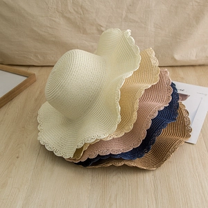 Detail of wavy scallop edges and textures on colorful woven paper straw sun hats