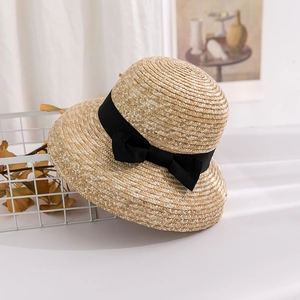 Detail of hand-woven straw sun hat showing fine natural texture and black ribbon bow