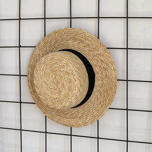 Detailed close-up of natural wheat straw texture and black ribbon on a boater hat