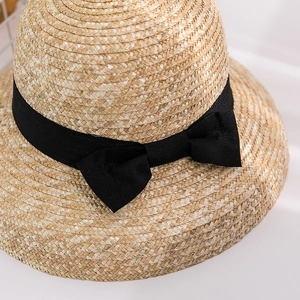 Detail shot of the fine straw weaving texture and black ribbon bow on a sun hat