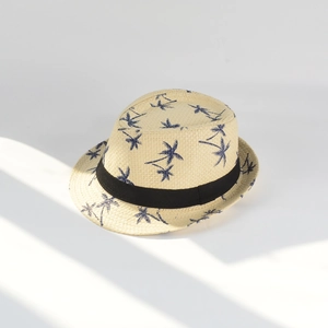 Detailed macro shot of beige straw fedora with blue palm tree patterns and black ribbon