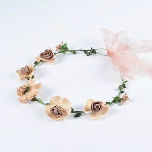 Detail eines handgefertigten Blumenstirnbands mit champagnerfarbenen Blüten und Band