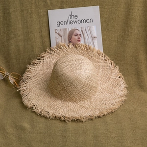 Gros plan d'un chapeau de paille en raphia naturel avec bords effilochés sur tricot