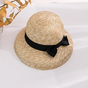 Close-up of natural straw sun hat with black ribbon bow and fine woven texture