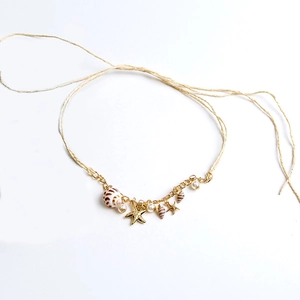 Bohemian seashell and starfish necklace with golden chain and pearls on white background