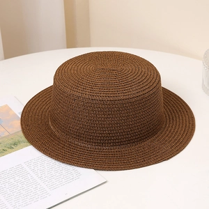Dark brown straw flat top boater hat with woven texture on a minimalist table