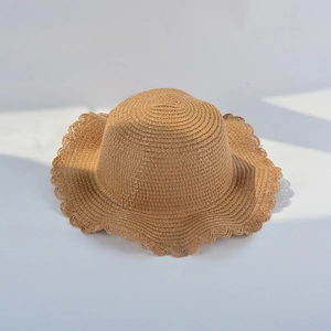 Elegant summer straw hat for girls with wavy brim and floral accent on gray background