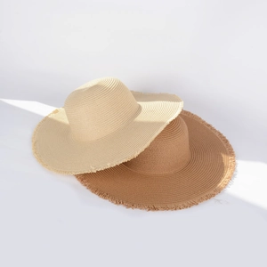 Detailed macro view of woven straw hats featuring fringed edges in beige and brown tones