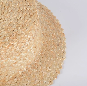 Détail macro du tressage en paille naturelle et bordure dentelée du chapeau de paille plat