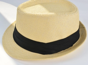 Detail of light beige straw fedora hat with a black grosgrain ribbon and fine texture