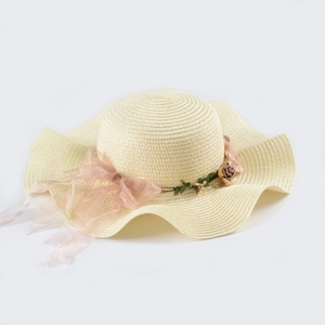 Detail of a wide wavy brim sun hat featuring pink organza ribbon and delicate floral accents