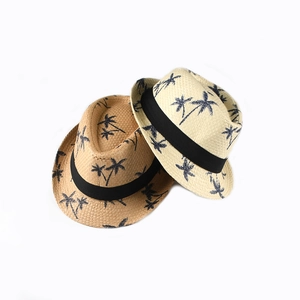 Detail of woven straw fedoras with dark palm tree prints and black ribbon bands