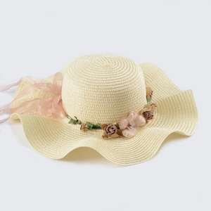 Detail of hand-woven straw hat featuring pink fabric floral garland and chiffon ribbon