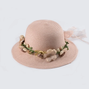 Dettaglio del cappello di paglia con ghirlanda di fiori rosa e nastro di chiffon