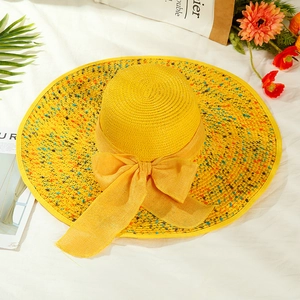 Detailed top view of a yellow straw hat with a wide brim, ribbon bow and floral accents