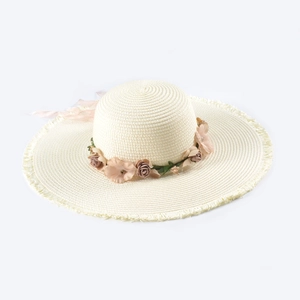 Close-up of summer straw hat with silk flowers, ribbon bow and fringed brim detail